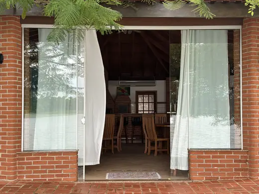Entrada do Espaço Bell com portas de vidro e cortinas brancas