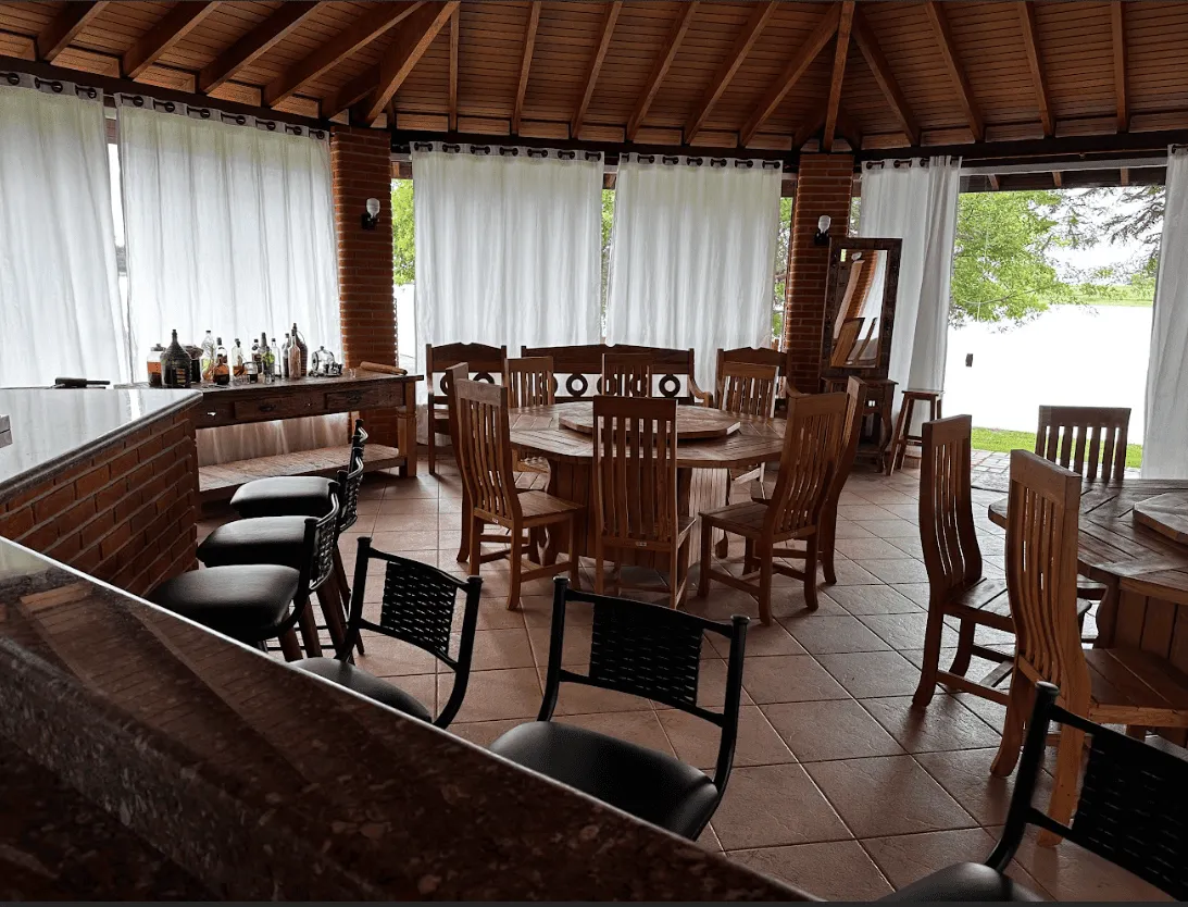 Interior do Espaço Bell com bar, mesas de madeira e vista para o lago